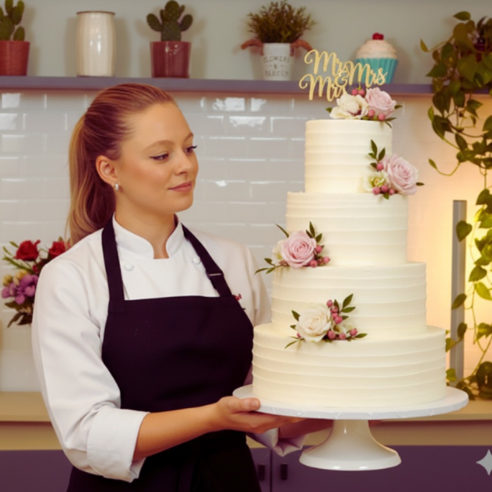 Beatriz segurando um bolo de casamento de quatro andares com flores