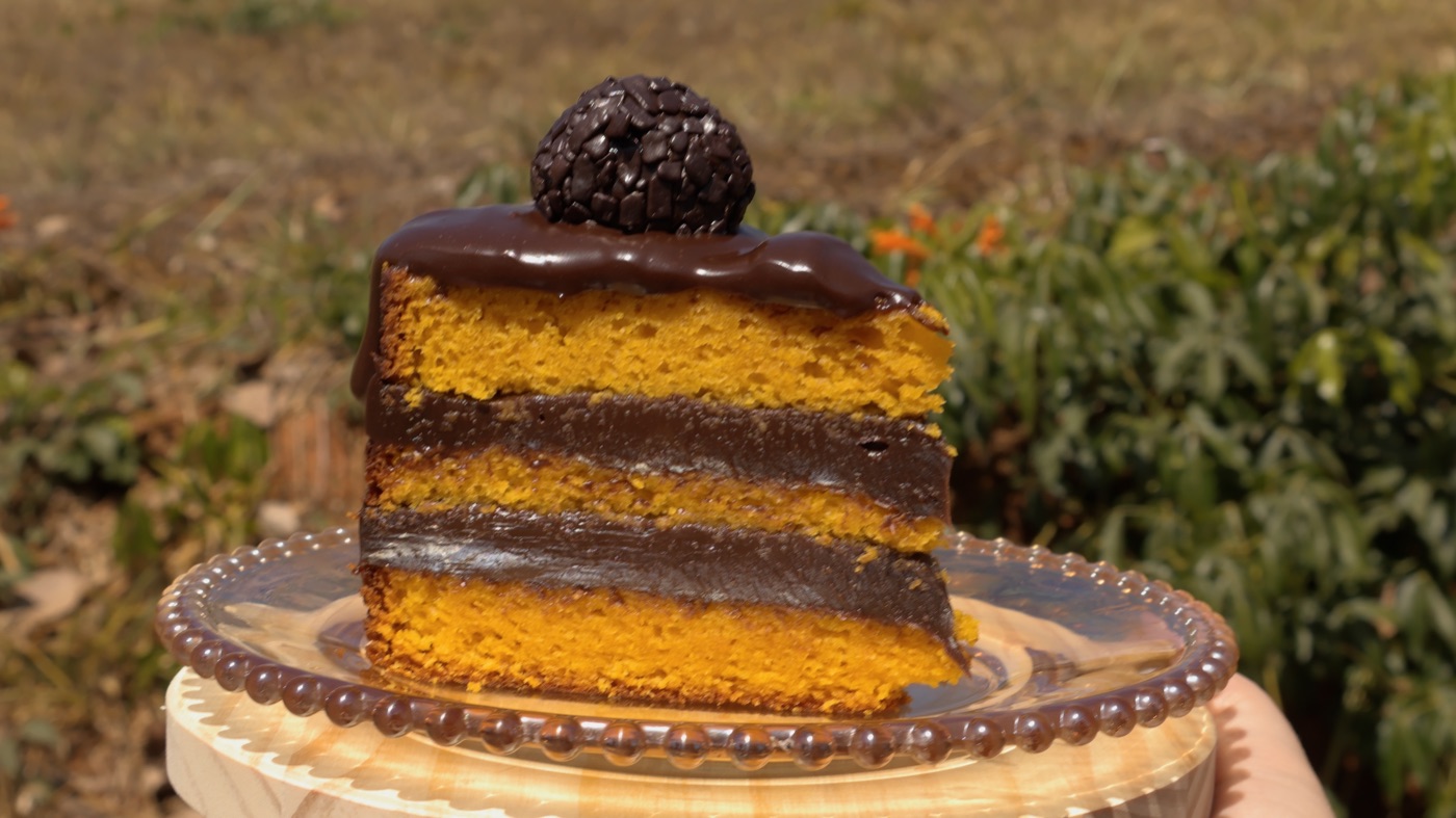 Fatia de bolo de cenoura em camadas com recheio de brigadeiro e um brigadeiro no topo